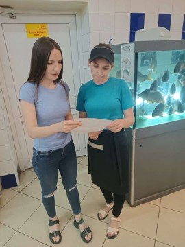 на фото дві жінки біля акваріуму