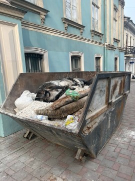 на малюнку зображено сміттєвий бак в якому лежить опудало корови