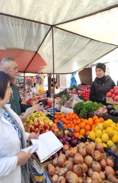 на малюнку - три людини біля ятки з овочами і фруктами