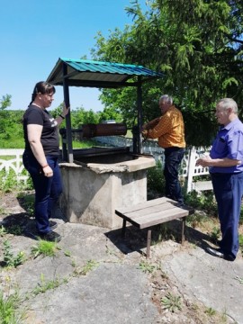 на фото - три людини біля криниці