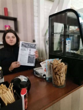 На малюнку дівчина за барною стійкою кав'ярні тримає в рухах пам'ятку про місця для куріння
