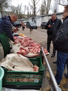 На малюнку зображені люди біля торгової ятки з м'ясом