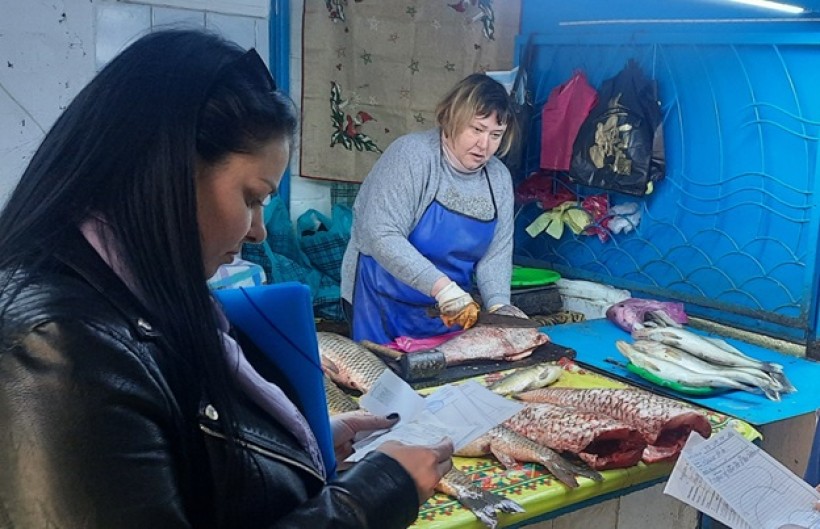 на малюнку - дві жінки біля прилавку зі свіжою рибою