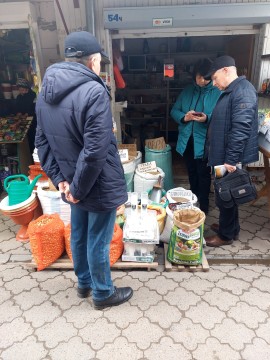 На малюнку зображено 2 чоловіка і жінку біля мішків з насіннєвим матеріал