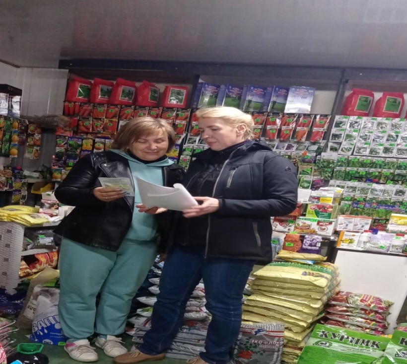 на малюнку дві жінки біля прилавку з насінням в пакетиках