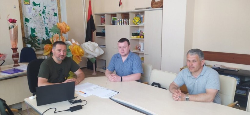на фото - три чоловіка за столом