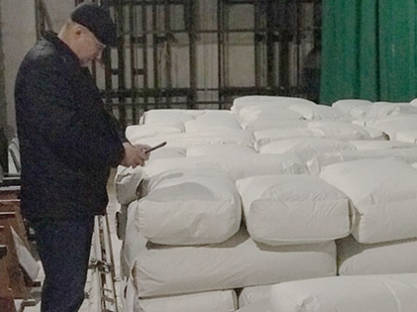 На малюнку зображено чоловіка біля купи мішків білого кольору
