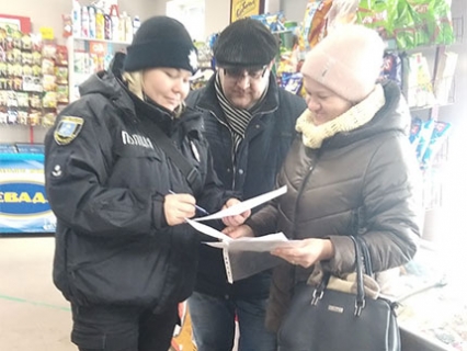 На фото зображено поліціантку і двох людей в магазині.