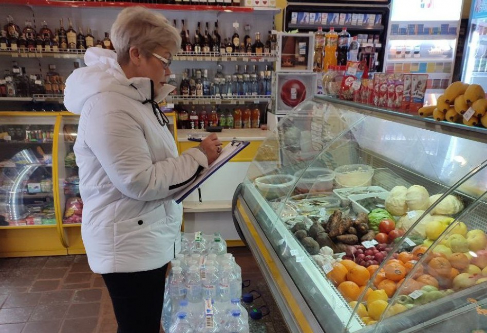 на малюнку - жінка з папкою в супермаркеті біля прилавку з овочами