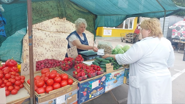 на фото - дві жінки біля ятки з овочами і ягодами